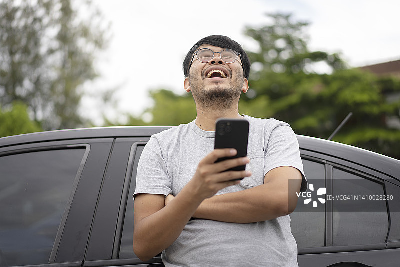 亚洲年轻旅行者靠车用手机图片素材