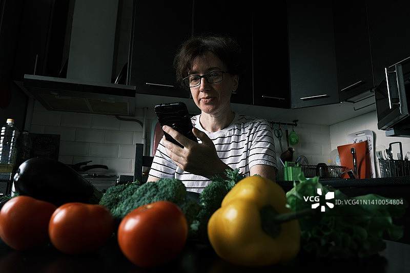 女人正在打开刚买的新鲜蔬菜并打电话图片素材