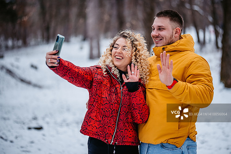 年轻情侣在雪林中进行视频通话图片素材