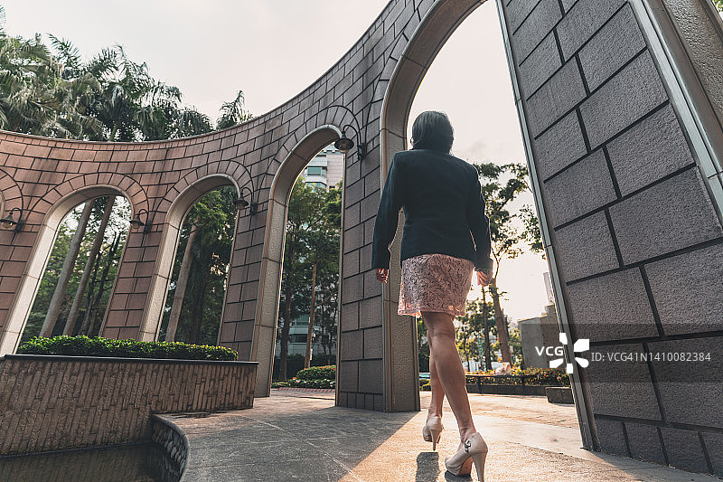 亚洲女商人在现代办公楼附近行走图片素材