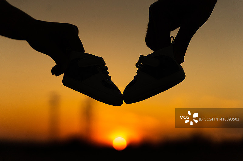 日出时分情侣在田野上手持婴儿鞋图片素材