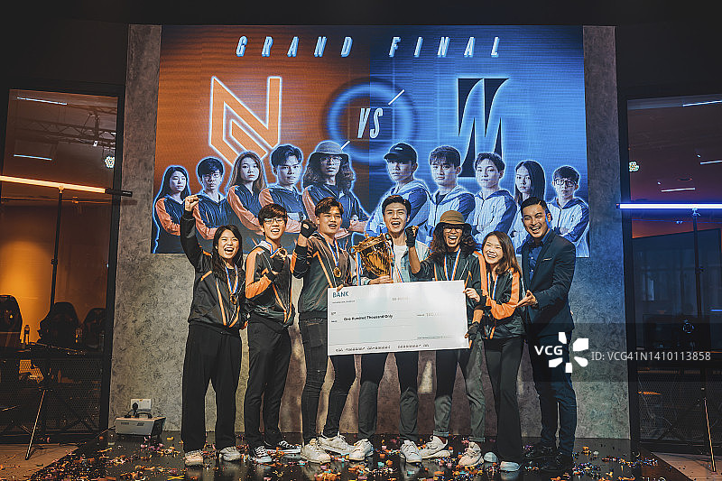 亚洲电竞获胜团队在总决赛舞台上对着镜头微笑的合影。电子游戏锦标赛竞技场。网络游戏赛事图片素材
