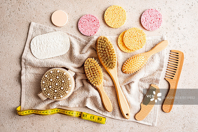 用于干刷按摩的木制身体刷、清洁海绵、发刷、丝瓜络海绵、卷尺和浴巾在混凝土背景上，顶视图，居家水疗概念，零浪费，身体护理，平放图片素材