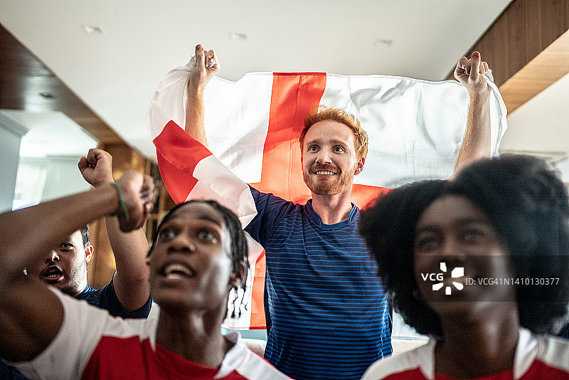 在家观看比赛并举着英国国旗庆祝的运动迷图片素材