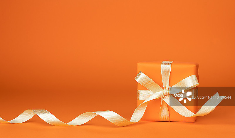 橙色背景上的节日礼品盒，带有留白空间图片素材
