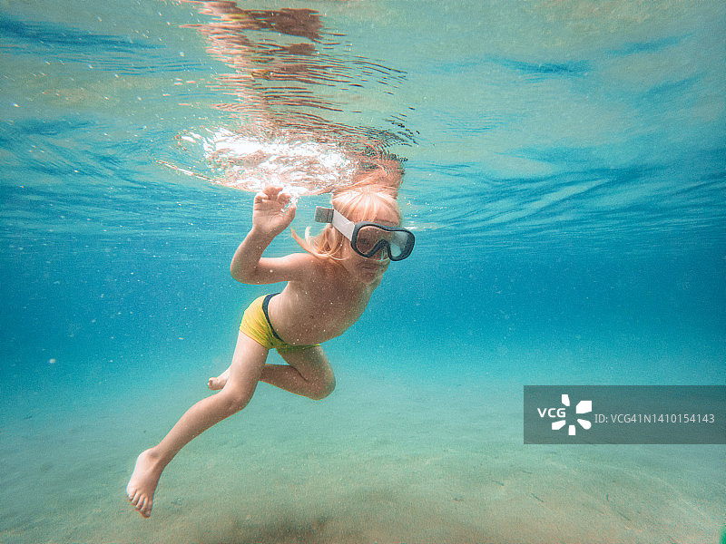 戴着护目镜在水下游泳的男童图片素材