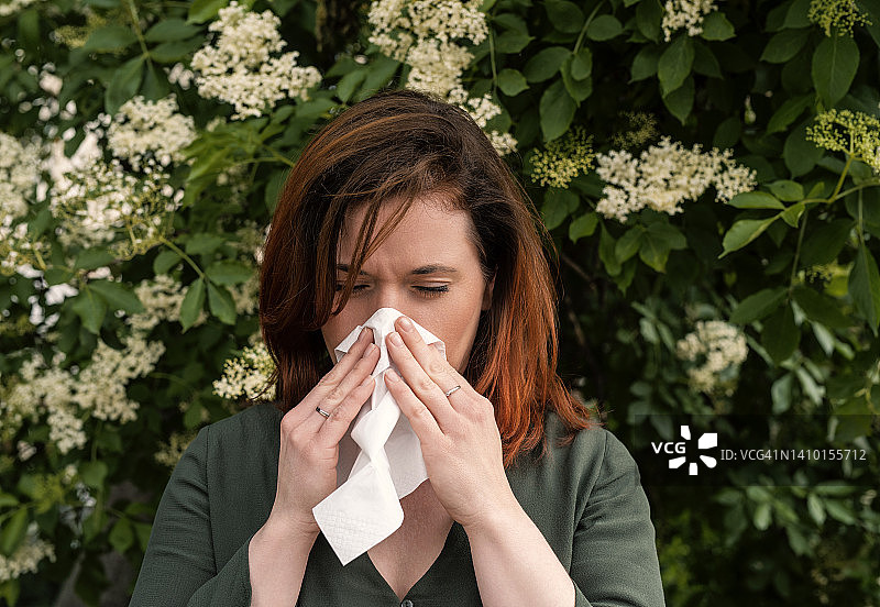 患有花粉热并对着手帕打喷嚏的红发女子图片素材