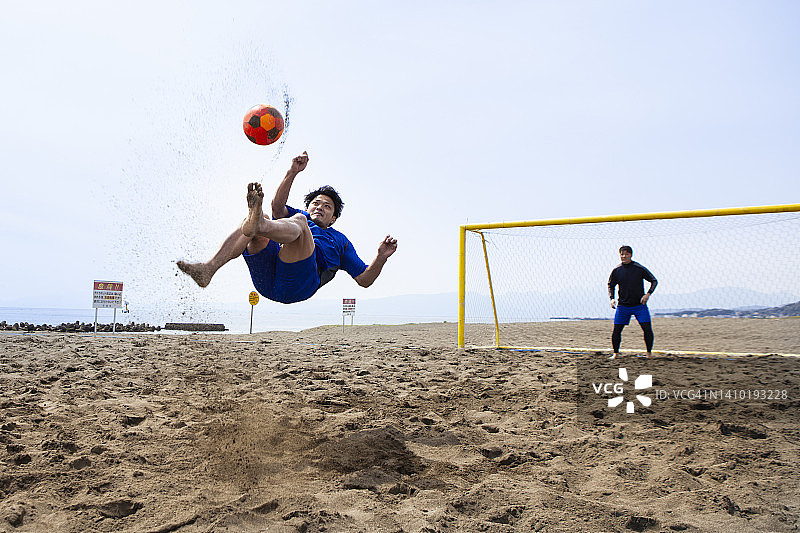 在空中踢球的海滩足球运动员图片素材