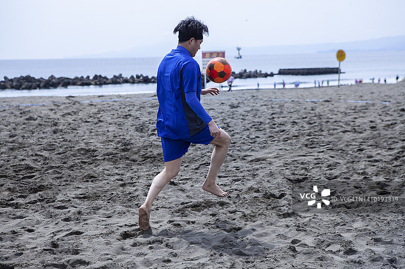 在海滩上举重的足球运动员图片素材