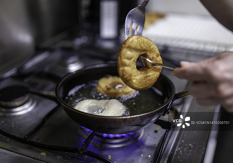 在装满热油的平底锅中烘烤甜甜圈图片素材