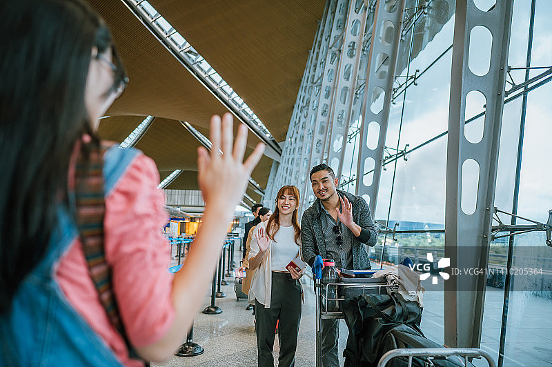 欢迎回来，爸爸妈妈。快乐的年轻亚裔中国女孩在机场到达大厅挥手迎接父母图片素材