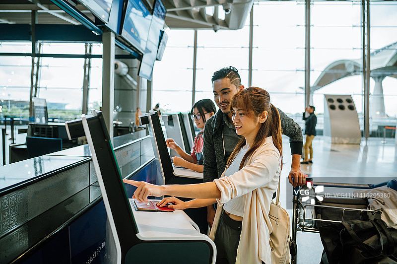亚洲情侣在机场航站楼使用触摸屏确认身份图片素材