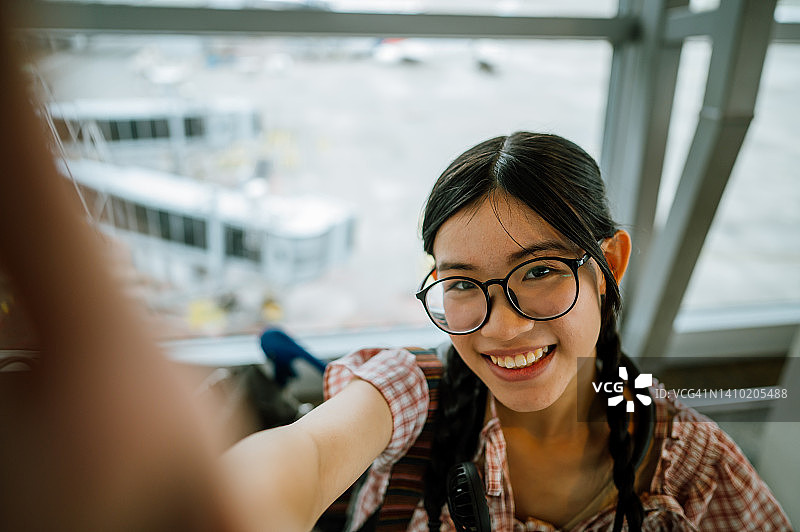 年轻的亚裔中国女孩在机场航站楼自拍特写图片素材