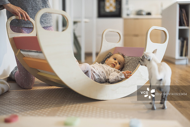 女宝宝坐在摇椅上，看着她的狗狗图片素材