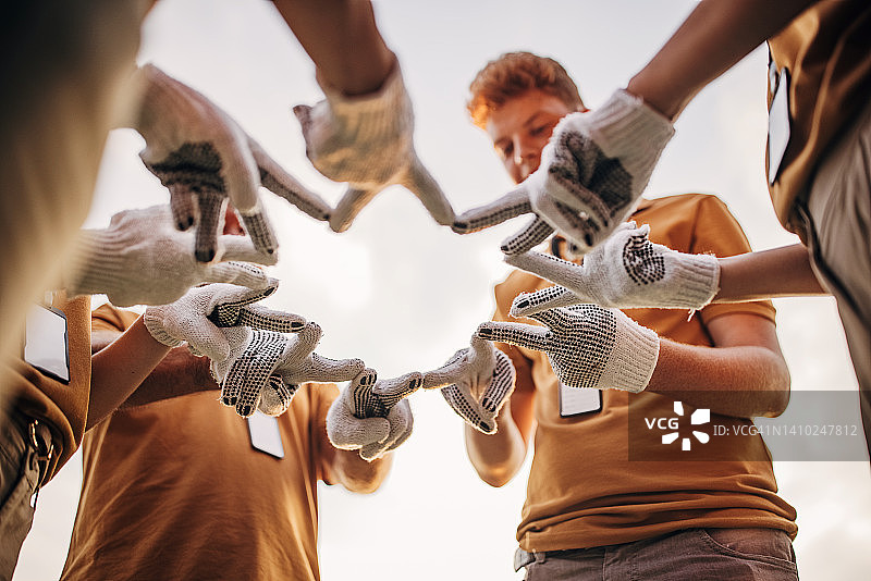 一群志愿者围成一圈，共同做出和平手势图片素材