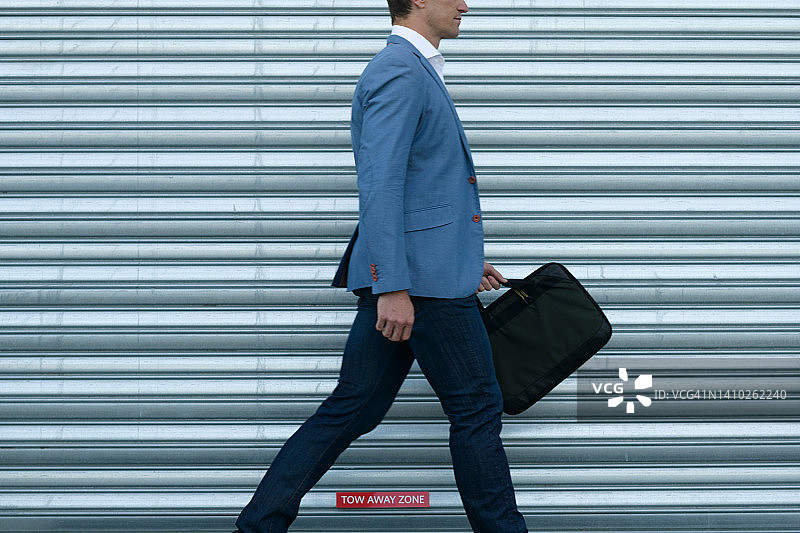 手提电脑包的商务男士走过车库门图片素材