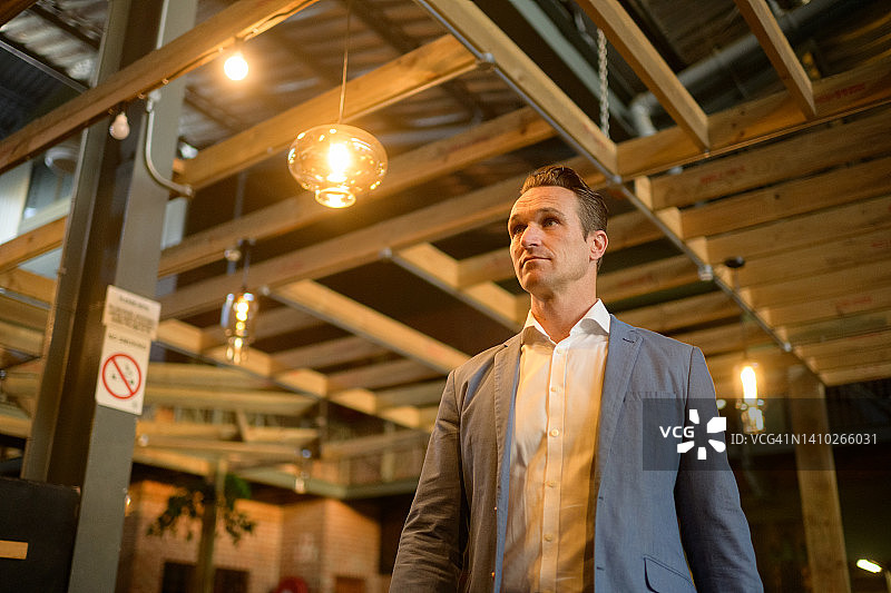 低角度拍摄的企业家走过室内悬挂的灯饰图片素材