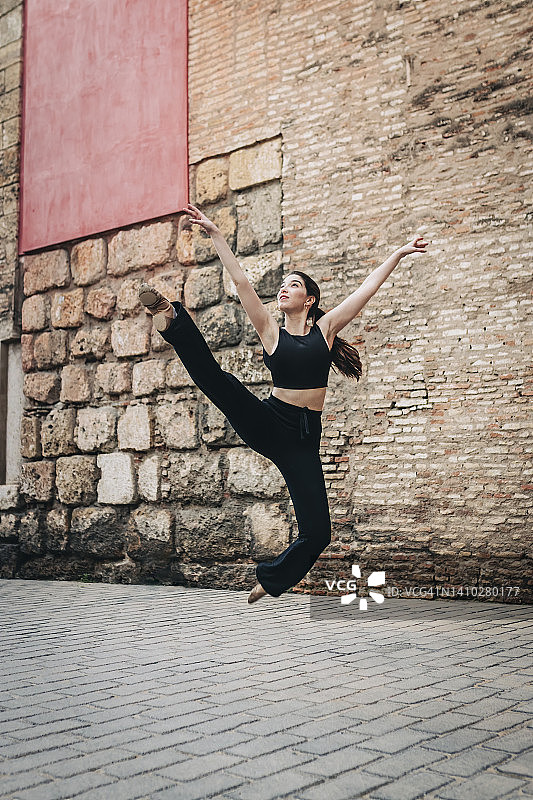 在砖墙附近练习芭蕾舞的女人图片素材