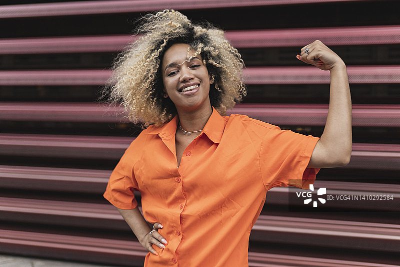 手放在臀部，在墙前展示肌肉的年轻女子图片素材