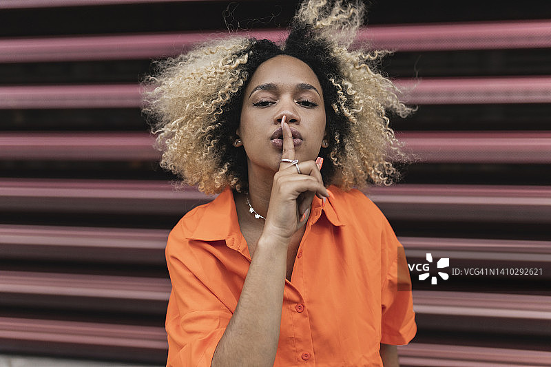 在墙前做安静手势的女人图片素材