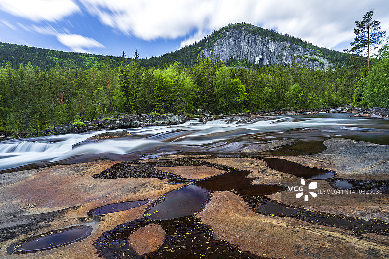 挪威西福尔-泰勒马克郡Tessungdalen：夏季河流的长时间曝光，背景是悬崖和绿色森林图片素材