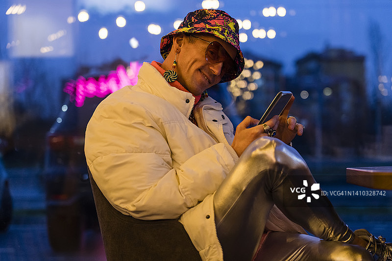 在酒吧使用智能手机的微笑男人图片素材