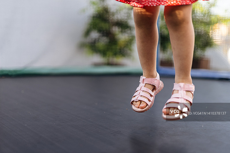 小女孩在蹦床上漂浮在空中图片素材