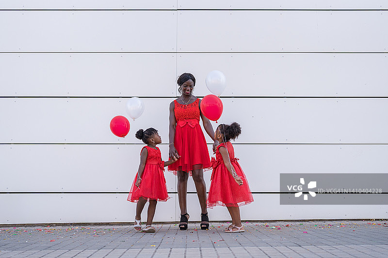 身穿红色服装、手持彩色气球的非洲裔美国家庭图片素材