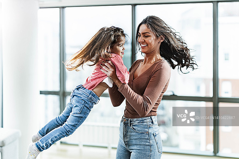 单亲妈妈在家旋转小女孩，玩得很开心图片素材
