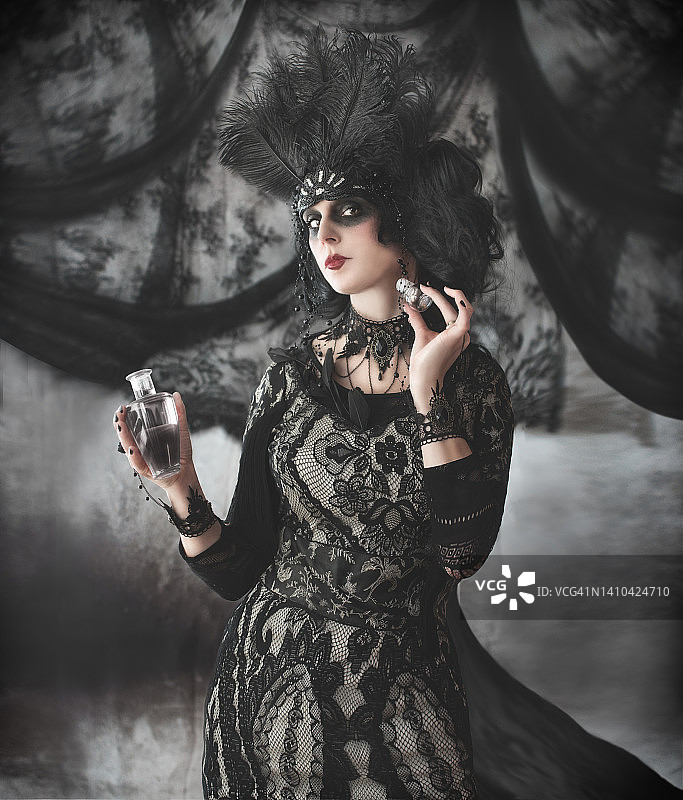 身着20年代风格黑色礼服和头饰的女人，手持香水喷雾瓶图片素材