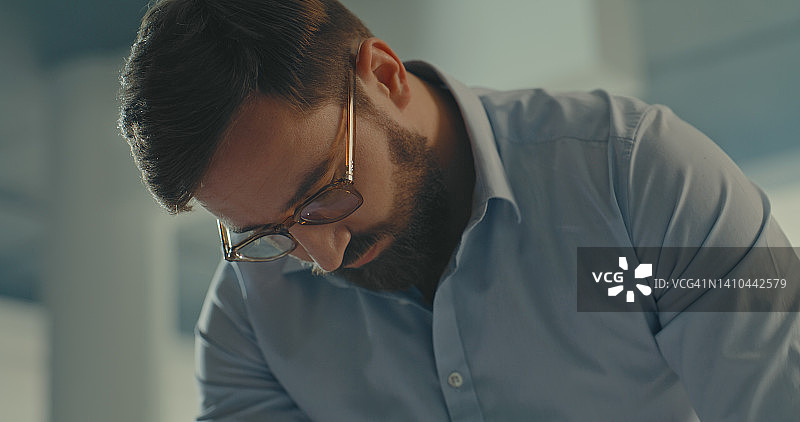 戴眼镜的商务人士特写，工作中分析重要文件图片素材