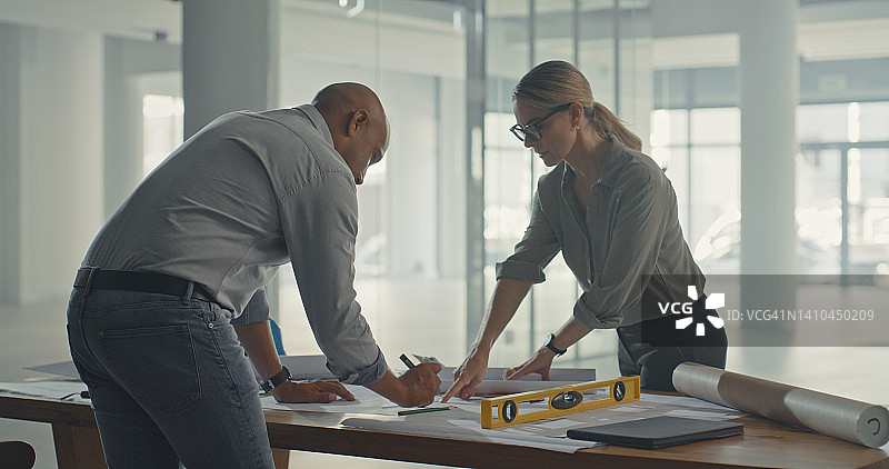 两位建筑师正在起草建筑和施工项目的蓝图计划。专注的工业设计师和工程师正在开发布局并调整房地产开发的测量结果图片素材