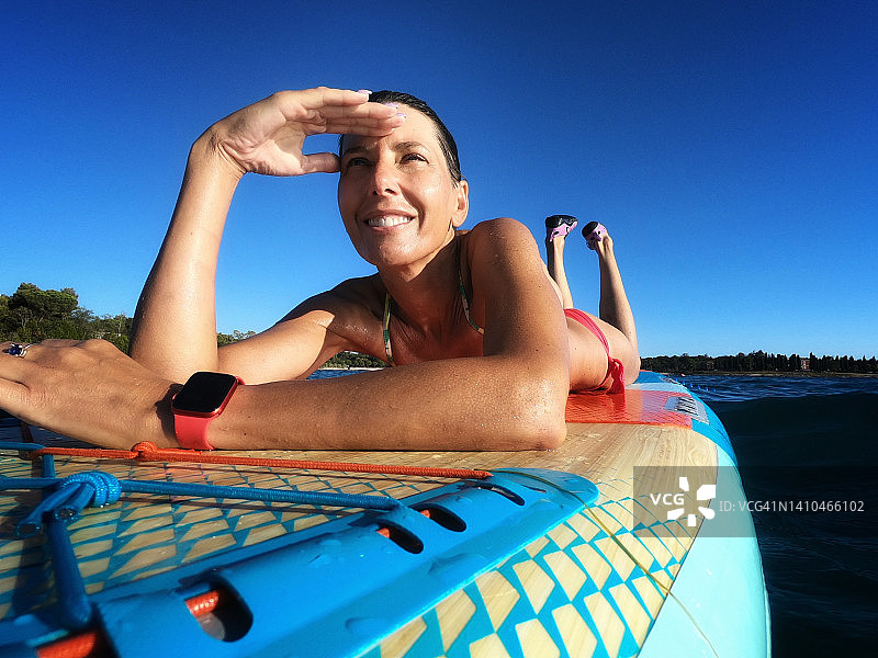 快乐的女人在桨板上放松图片素材