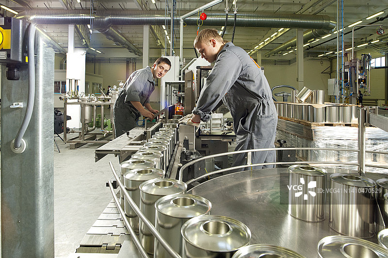 在油漆和清漆厂装配线上工作的两名年轻工人图片素材