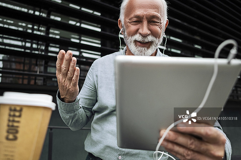 中年男人戴着耳机用平板电脑享受咖啡休息时间图片素材