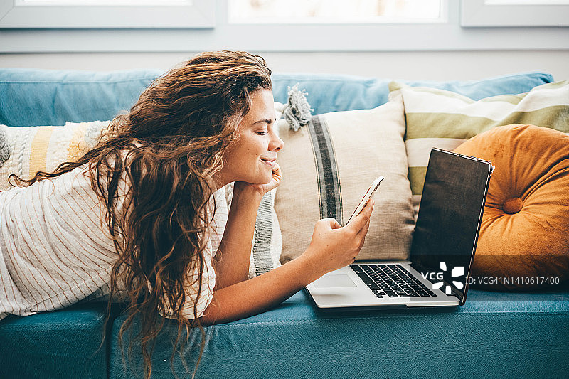 年轻女人在客厅工作，使用笔记本电脑图片素材
