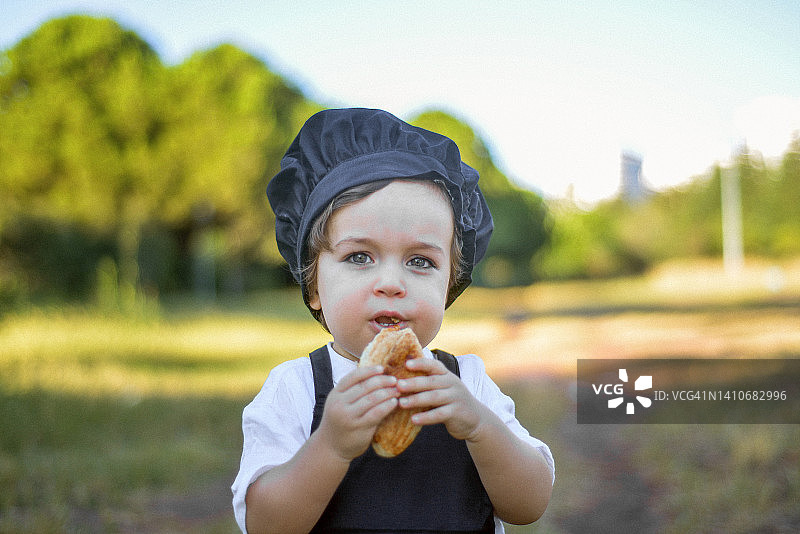 在公园里吃东西的可爱小厨师肖像图片素材