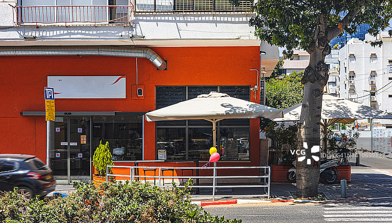 阳光明媚的中午，有着鲜艳橙色墙壁的街边咖啡馆图片素材