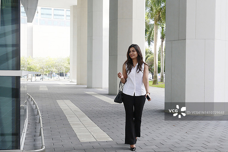 热带城市中穿职业装的长发巴基斯坦女人图片素材