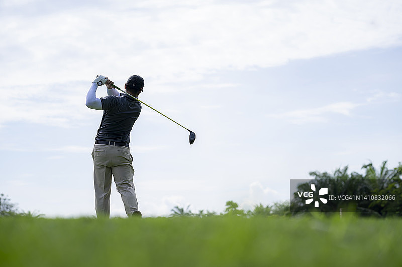 男人在球场上打高尔夫球，高尔夫球手击球向果岭图片素材