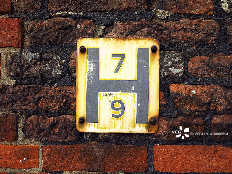 伦敦建筑外墙风化砖上的H形旧金属板图片素材