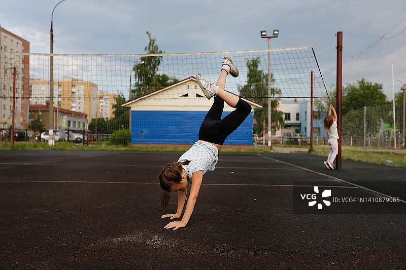 7岁儿童在城市运动场上用手做车轮图片素材