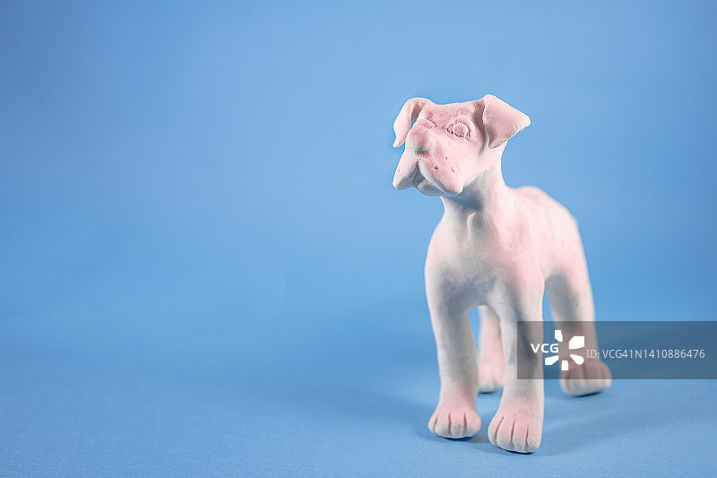 蓝色背景上的白色橡皮泥小狗，带复制空间。手工制作的宠物和兽医概念图片素材