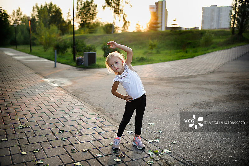 夏季，穿着紧身裤和运动鞋的幼儿在城市公园里做运动图片素材