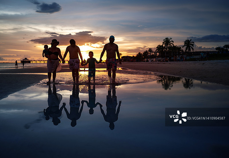 由5人组成的拉丁裔家庭在日落时分在海滩上散步图片素材