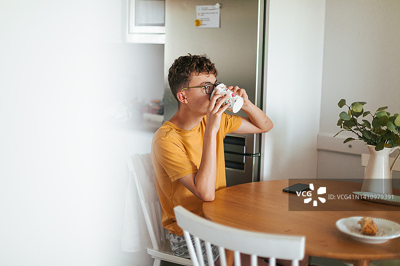 早上在家喝牛奶的青少年男孩肖像图片素材