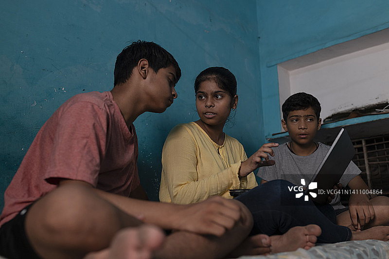 少女用笔记本电脑教她的弟弟们图片素材