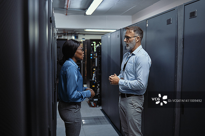 两位IT服务器技术员在数据中心讨论软件和恶意软件系统图片素材