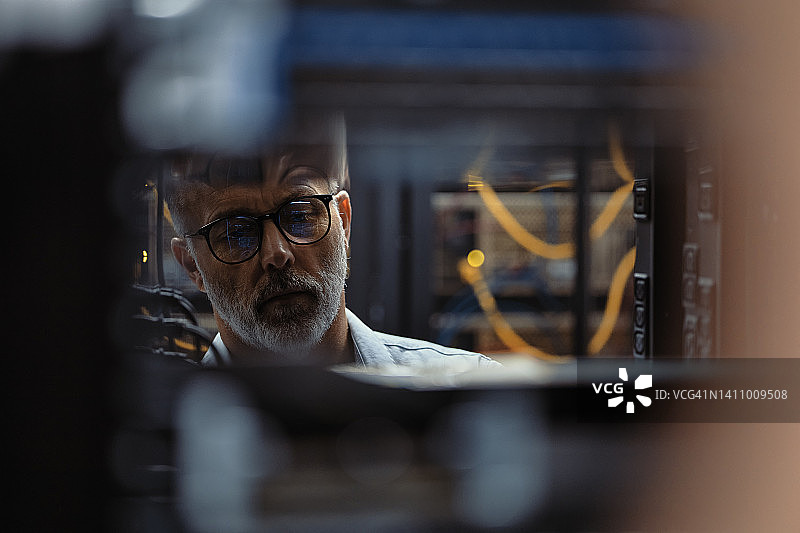 年长的IT服务器技术员在晚上修复数据中心图片素材