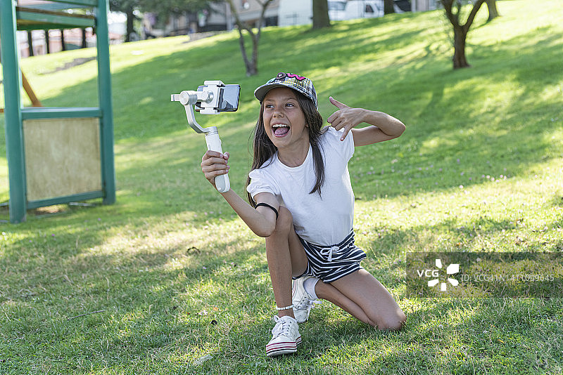女孩在公园里使用智能手机和稳定器拍摄视频图片素材